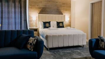 Ein Hotelzimmer mit einem Bett, zwei Nachttischen, einem blauen Sofa und einer Wand mit Holzelementen.