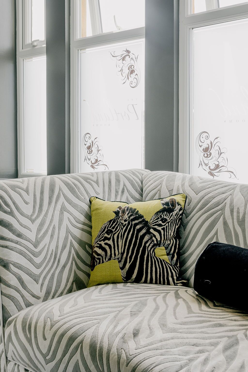 A sofa with a zebra pattern, a yellow pillow, and a black pillow.