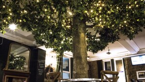 A tree with lights in a room with a round table and chairs, a mirror, and a sign on the wall. - The Portland Hotel (Ashington)