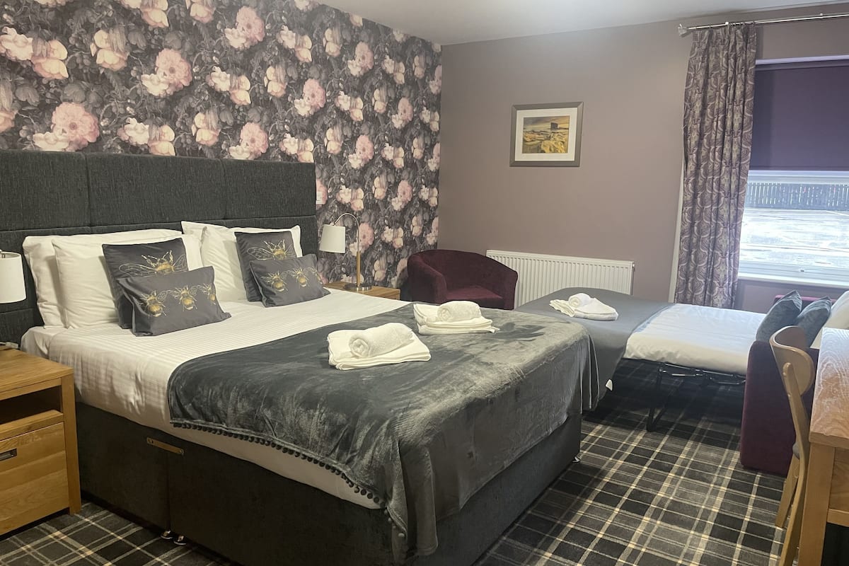 Quarto de hotel com cama, cadeira, mesa e janela com cortinas.