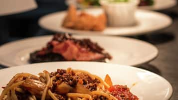 Une table garnie de différents plats, notamment des spaghettis à la viande et aux légumes, ainsi que d’autres assiettes contenant divers aliments.