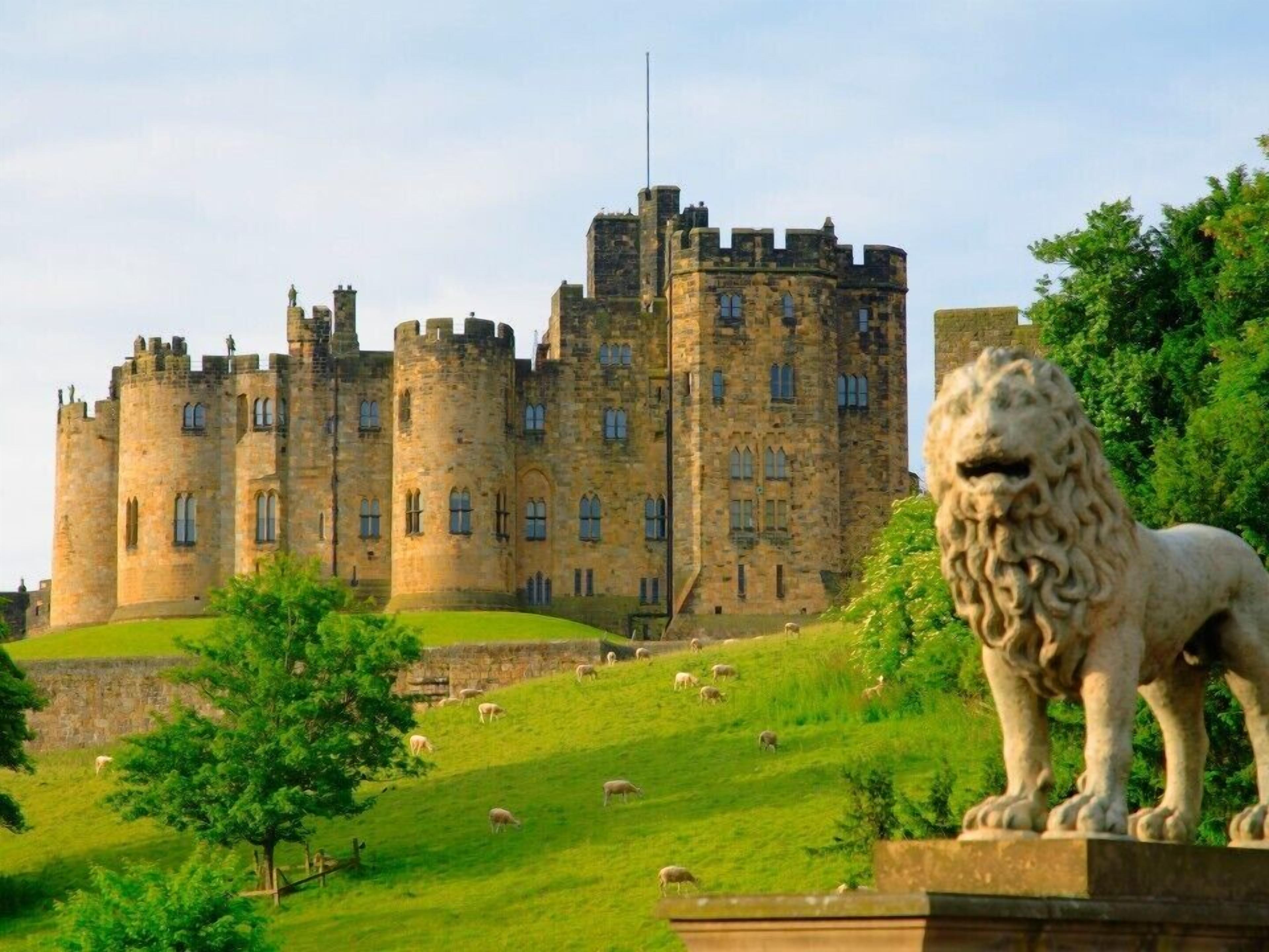 A castle with multiple towers and a lion statue in the foreground.