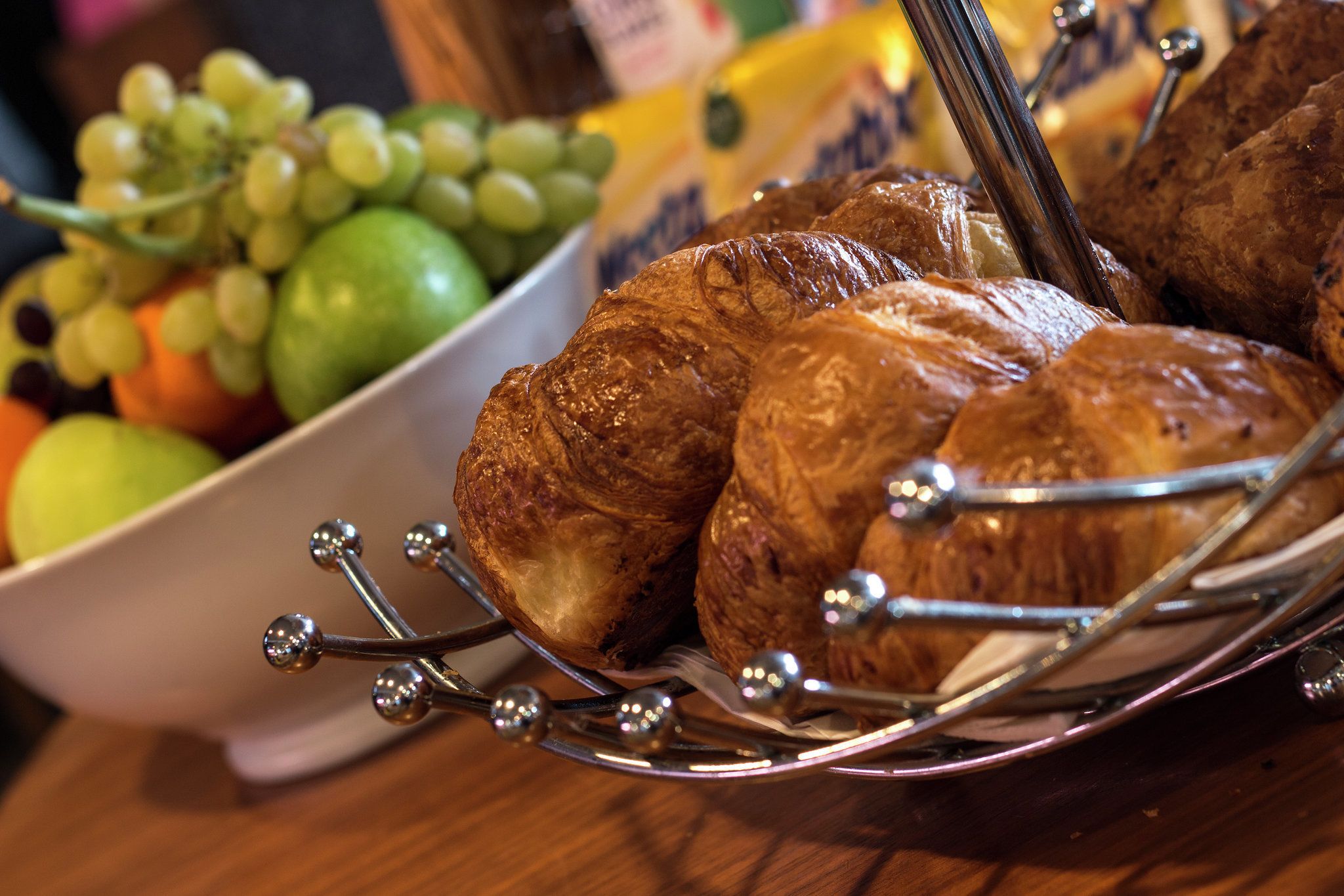 A basket of croissants and a bowl of fruit.