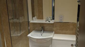 A modern bathroom with a glass-enclosed shower, a white sink with a mirror above it, and a toilet.