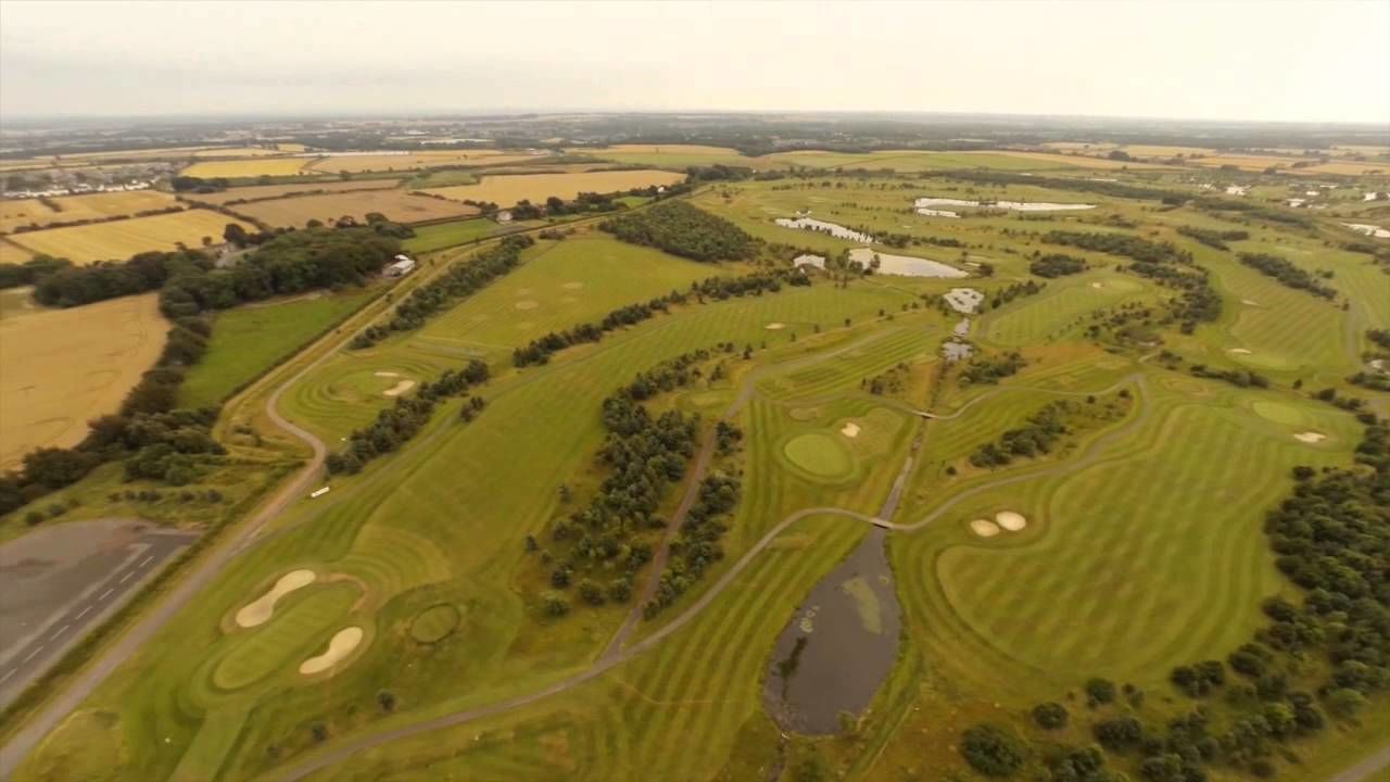 An aerial view of a golf course with multiple fairways, sand bunkers, and water hazards.