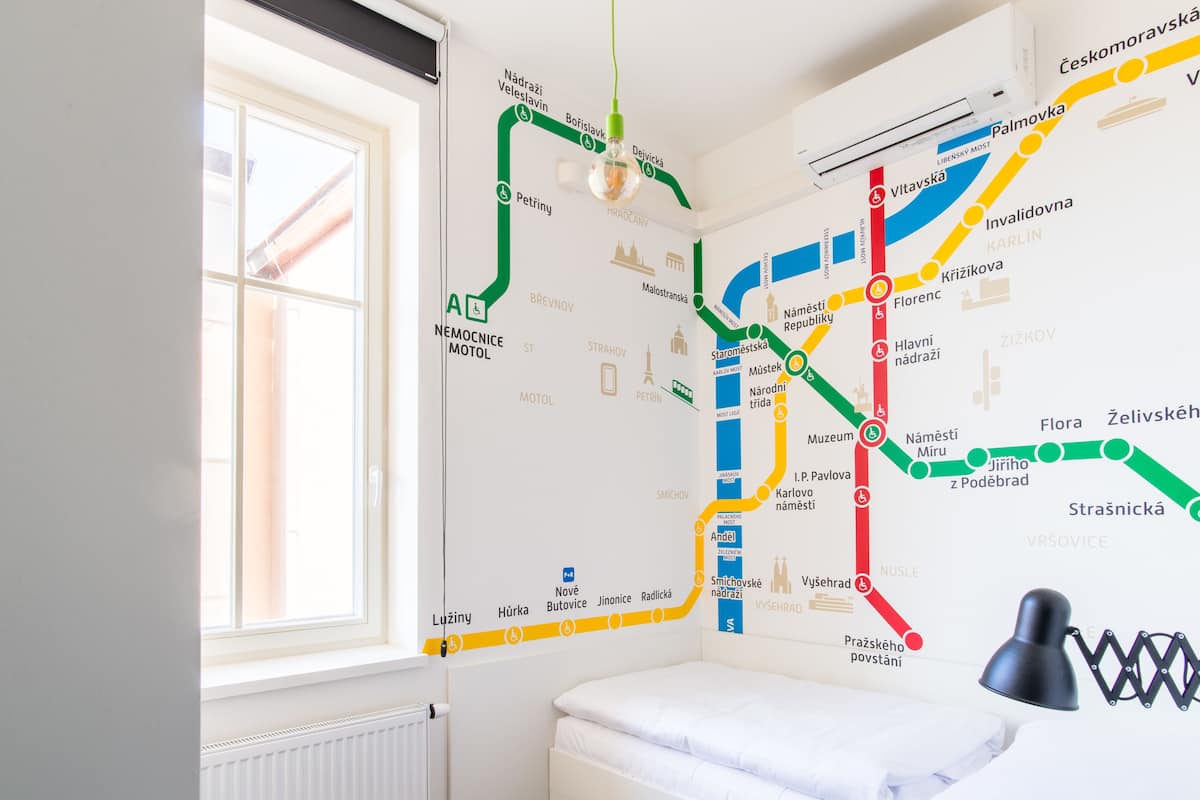 A bedroom with a large window, a bed, and a wall map of a city's metro system.