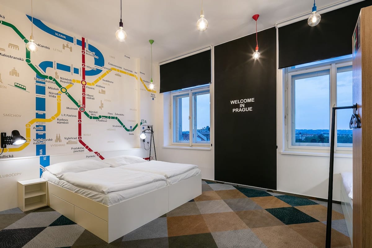 A modern hotel room with a large bed, a map on the wall, and a window with a view.