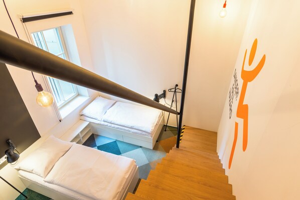 A bedroom with a bed, a window, and a staircase.