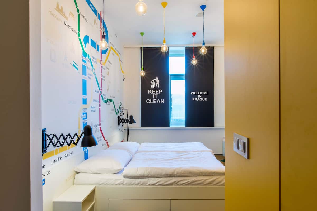 A hotel room with a bed, a map on the wall, and a window with a view.