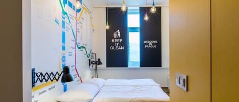 A hotel room with a bed, a map on the wall, and a window with a view.