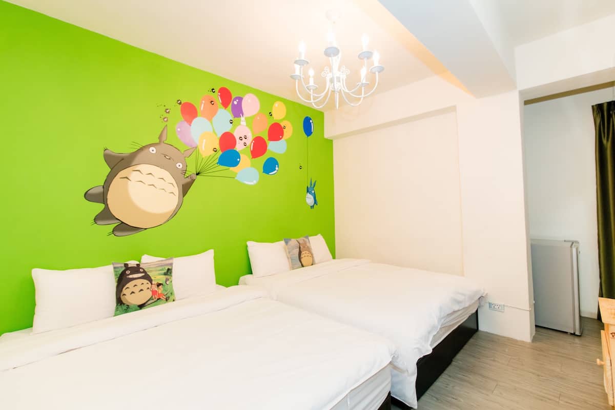 Ein Hotelzimmer mit zwei Betten, einer grünen Wand mit einer Zeichentrickfigur und einer Kandelaber.