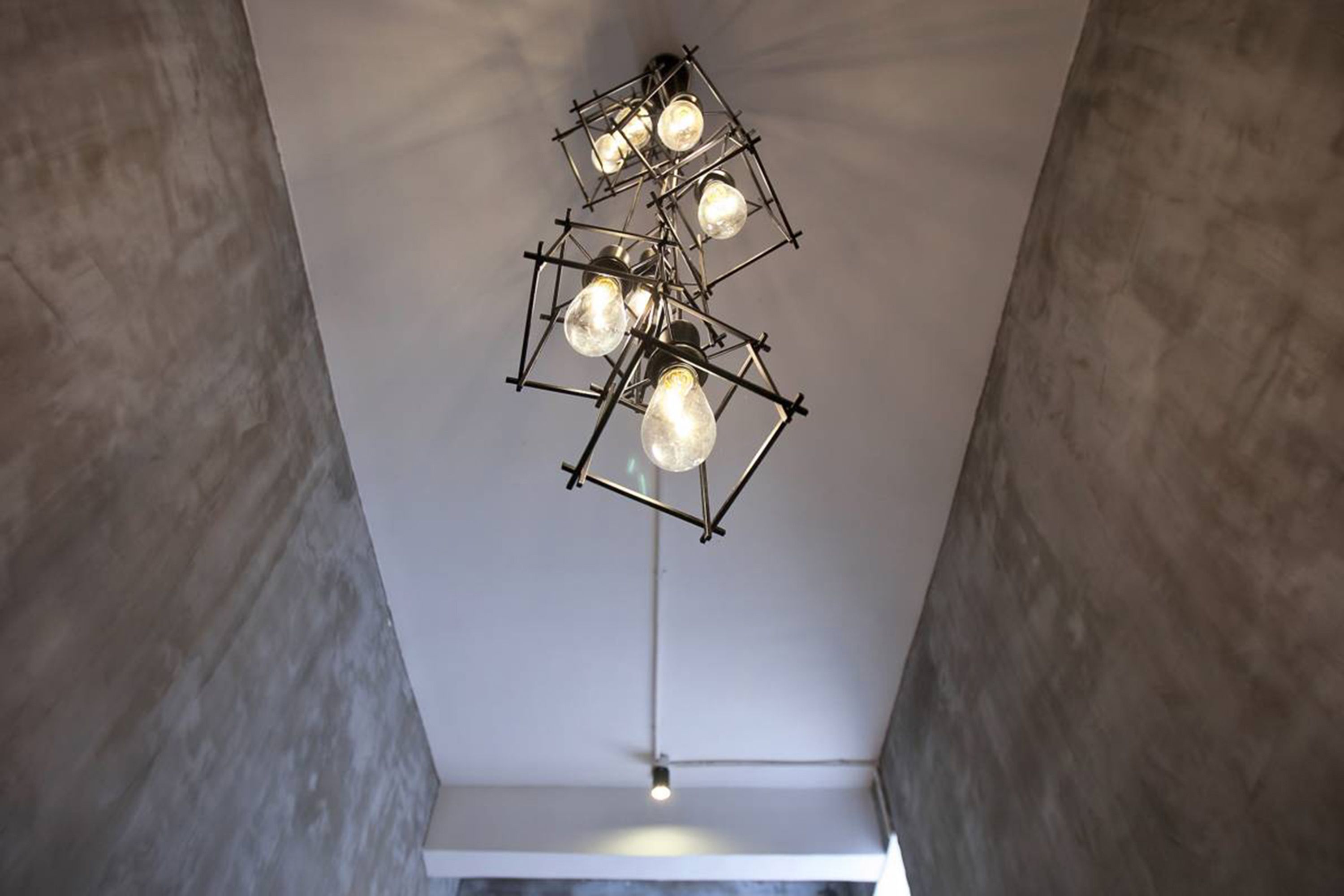 A modern ceiling light fixture with multiple bulbs, suspended from a geometric metal frame.
