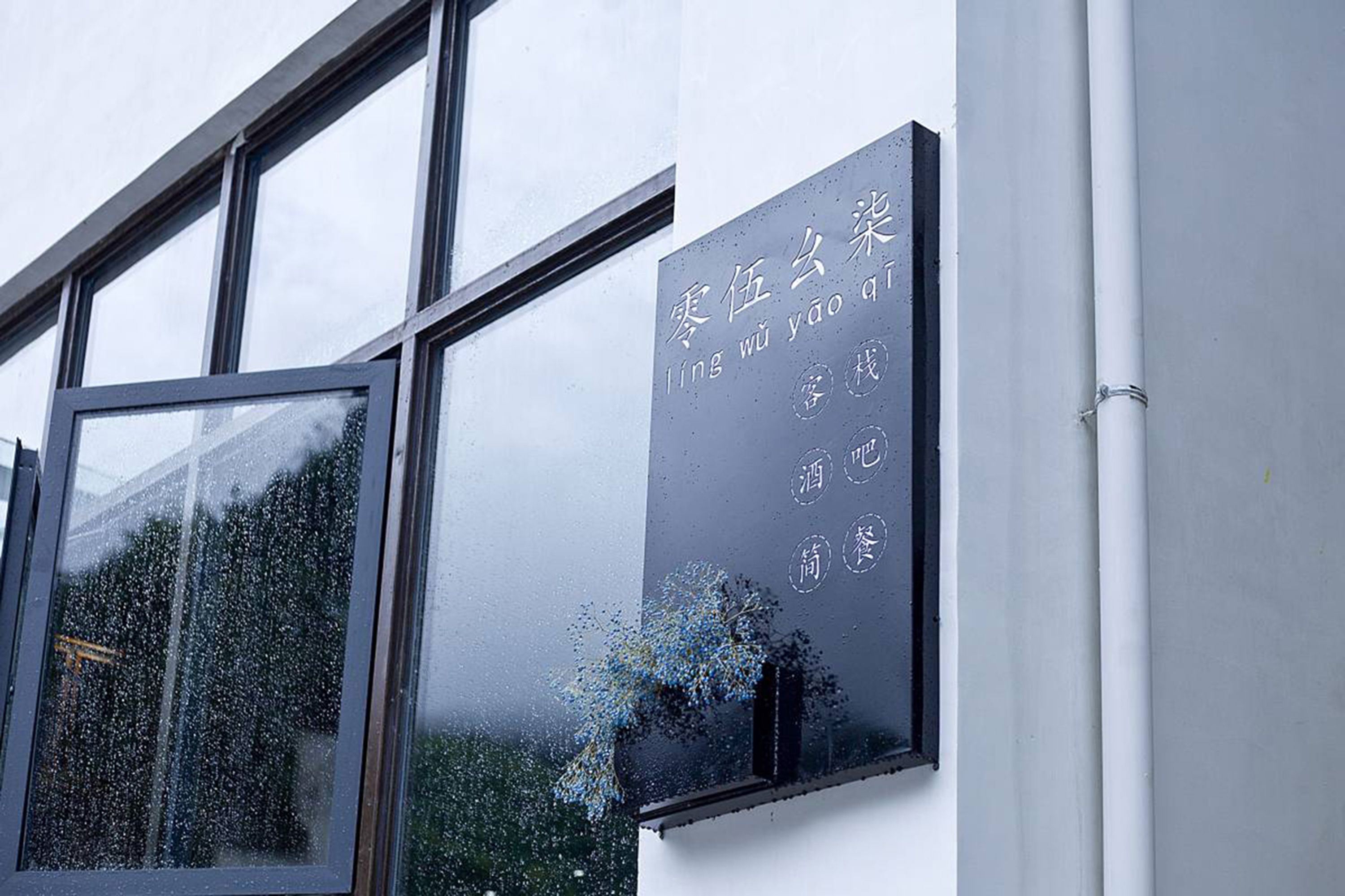 Fachada de edificio con grandes ventanales y un letrero con caracteres chinos.