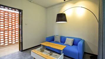 A modern living room with a blue sofa, a wooden coffee table, and a floor lamp.