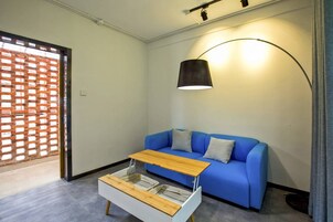 A modern living room with a blue sofa, a wooden coffee table, and a floor lamp.