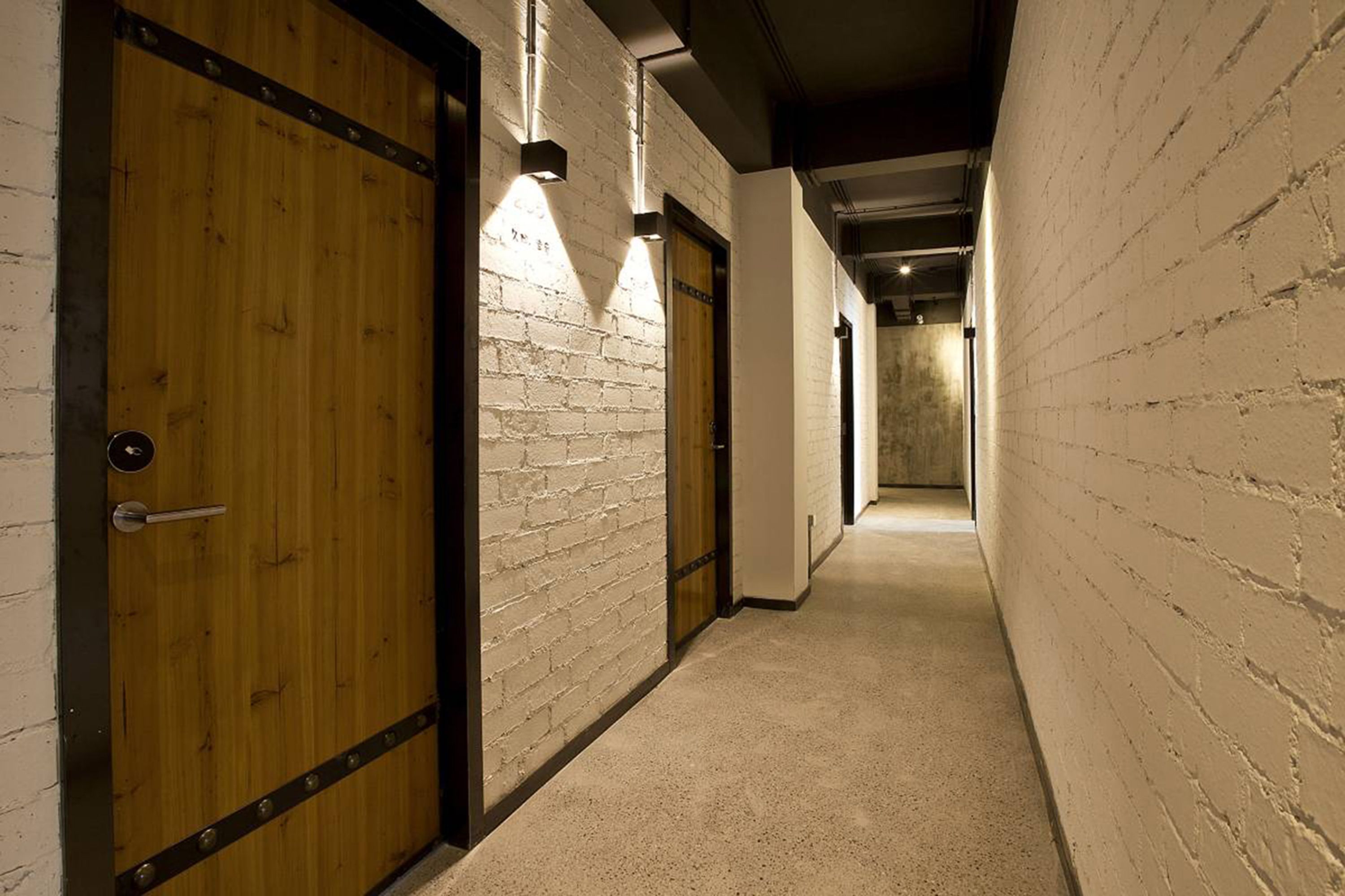 A hallway with wooden doors and white brick walls.