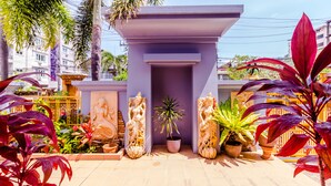 Un bâtiment moderne à la façade violette, entouré de plantes en pot et de sculptures.