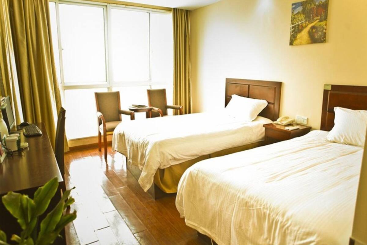 Habitación de hotel con dos camas, un escritorio con computadora, sillas y una ventana con cortinas.