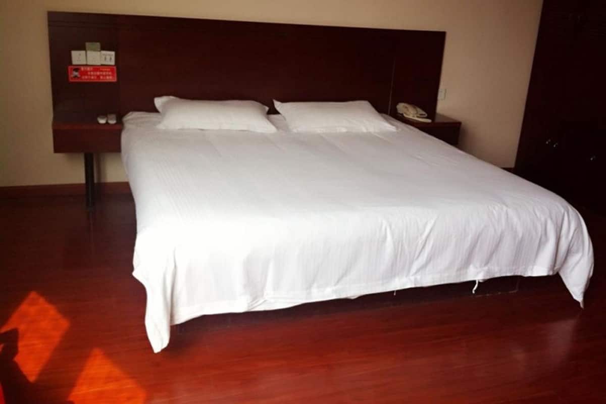 Una cama grande con ropa blanca en una habitación de hotel.