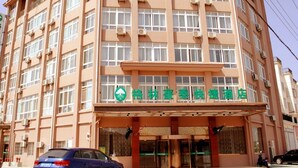 A multi-story hotel with a prominent entrance, air conditioning units, and a sign with Chinese characters. - GreenTree Inn Taizhou Xinghua Anfeng Runan Garden Express Hotel (Taizhou)