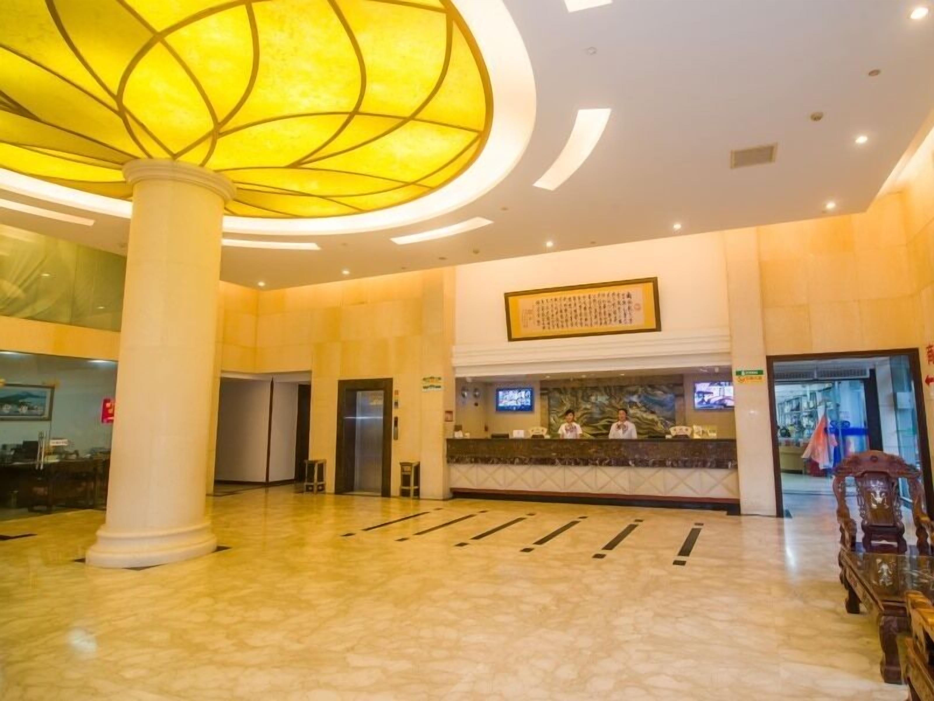 A spacious lobby with a large, illuminated ceiling feature, a reception desk, and a modern elevator.