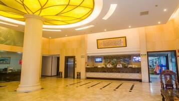 A spacious lobby with a large, illuminated ceiling feature, a reception desk, and a modern elevator.
