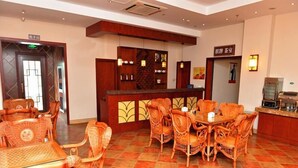 A lobby with wicker furniture, a reception desk, and tiled flooring. - GreenTree Inn Jiaxing Pinghu Zhapu Jiulong Mountain Express  Hotel (Jiaxing)