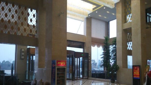 Un vestíbulo amplio con mostrador de recepción, zona de estar y una gran puerta de vidrio.