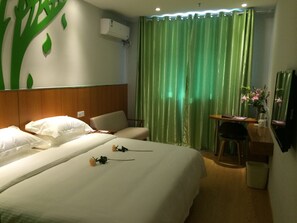 A hotel room with a bed, a desk, a chair, a trash bin, and a wall-mounted air conditioner. - Vatica TaiZhou JiangYan Bus Terminal Station East NanHuan Road Hotel (Taizhou)