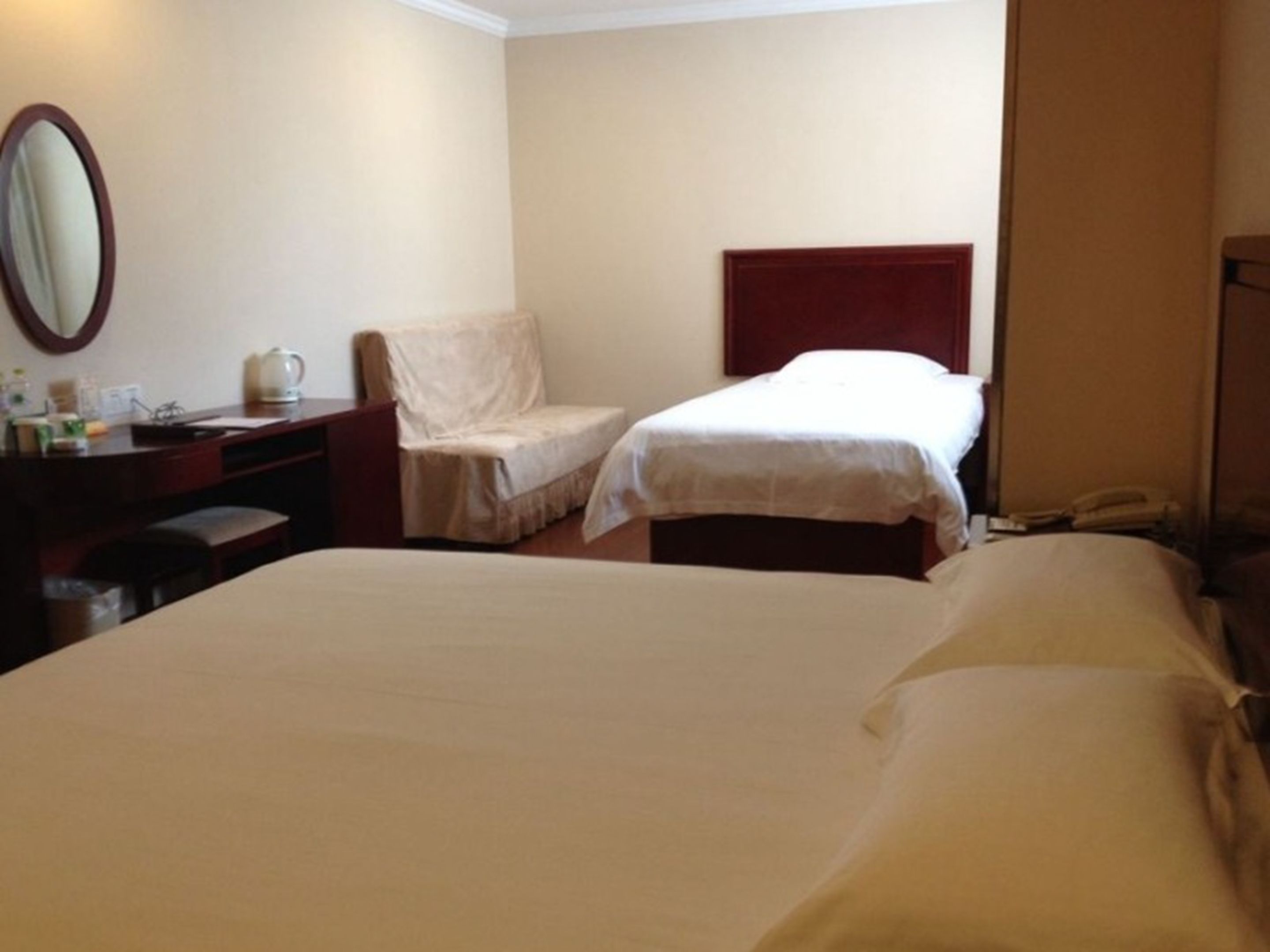 A hotel room with two beds, a desk with a telephone, and a chair.