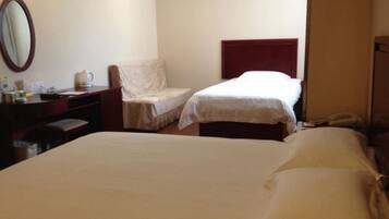 A hotel room with two beds, a desk with a telephone, and a chair.