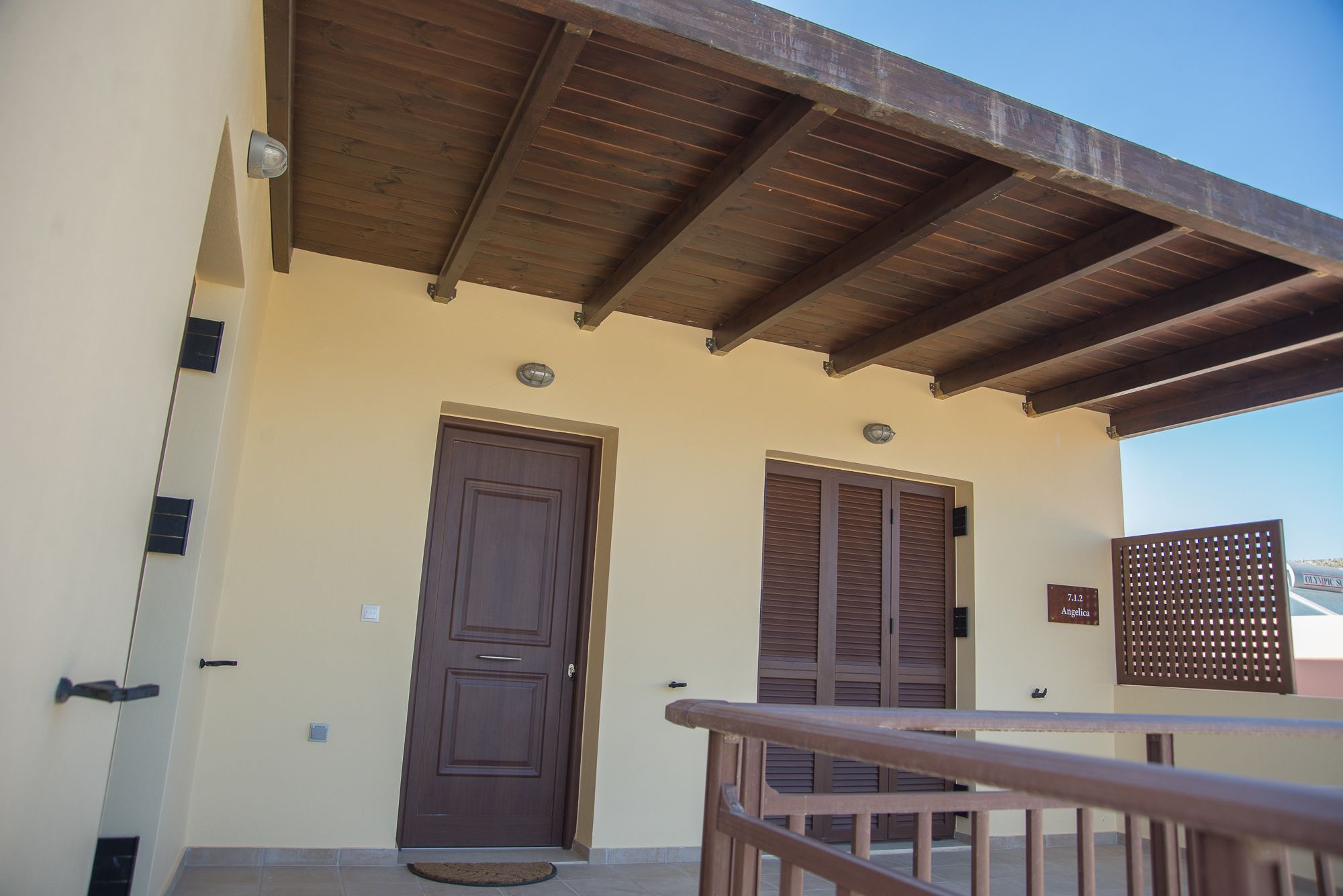 A building with a wooden balcony, a brown door, and a sign reading "Angelica."