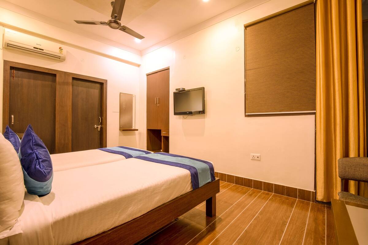 A bedroom with a bed, a ceiling fan, a TV, and a window with curtains.