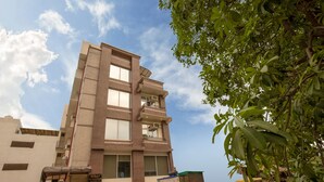 A multi-story building with a flat roof, a visible entrance, and a small outdoor area with a yellow vehicle. - Eclat Suites Mint Gomti Nagar (Lucknow)