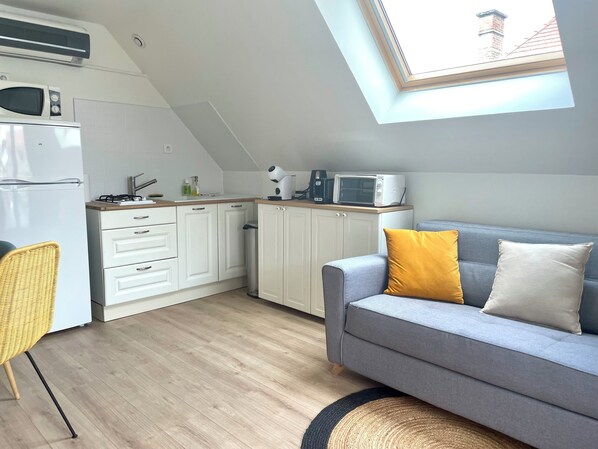 A compact kitchen with white cabinets, a microwave, and a gas stove. - Villa de la Croix (Villechétif)