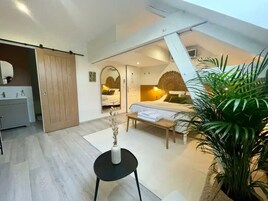 Un dormitorio con cama, mesita de noche y un espejo grande. Hay una puerta corredera que da al baño.