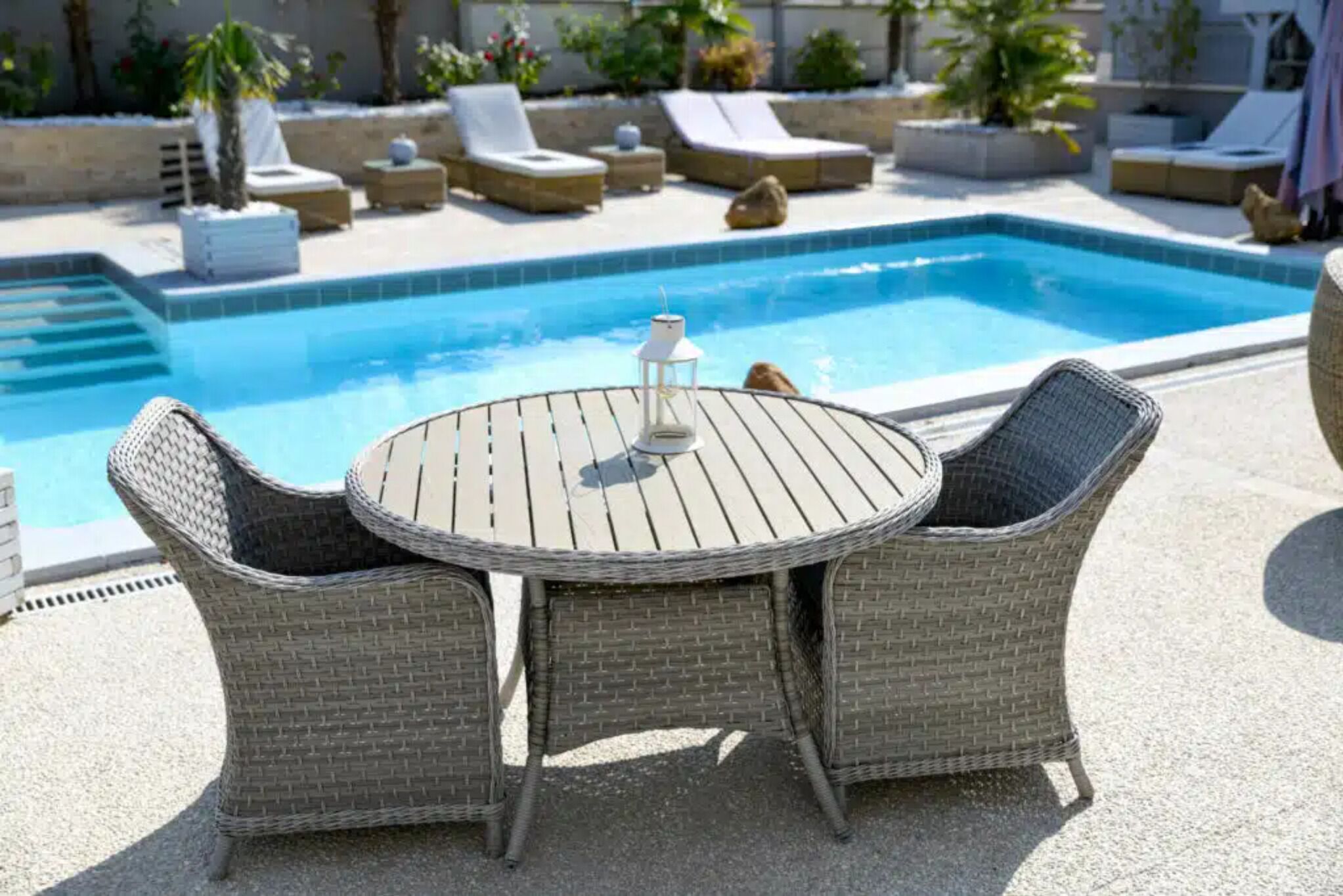 A poolside area with wicker furniture and a lantern.