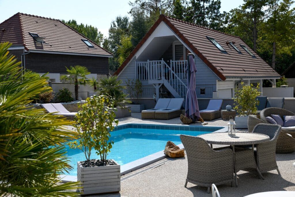 Un espace aménagé au bord de la piscine, comprenant une piscine, des chaises longues et un coin salon couvert avec un escalier.