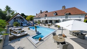 Een zwembadgedeelte met ligbedden, een tafel en parasols.