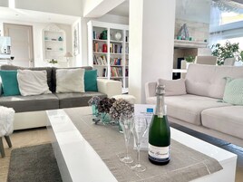 Una sala de estar moderna con un sofá gris, un sofá blanco y una mesa de centro con una botella de champán y dos copas.