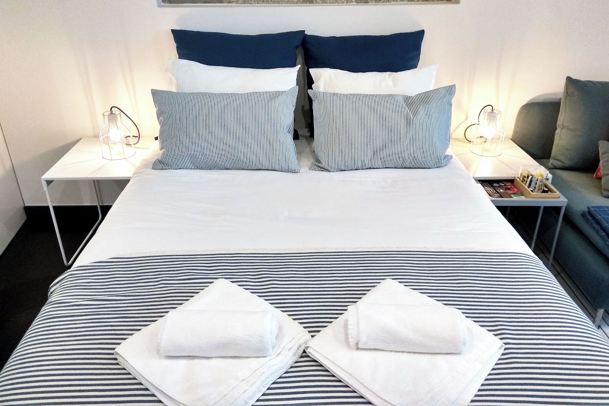 Una cama bien hecha con ropa de cama a rayas, dos almohadas y dos toallas.