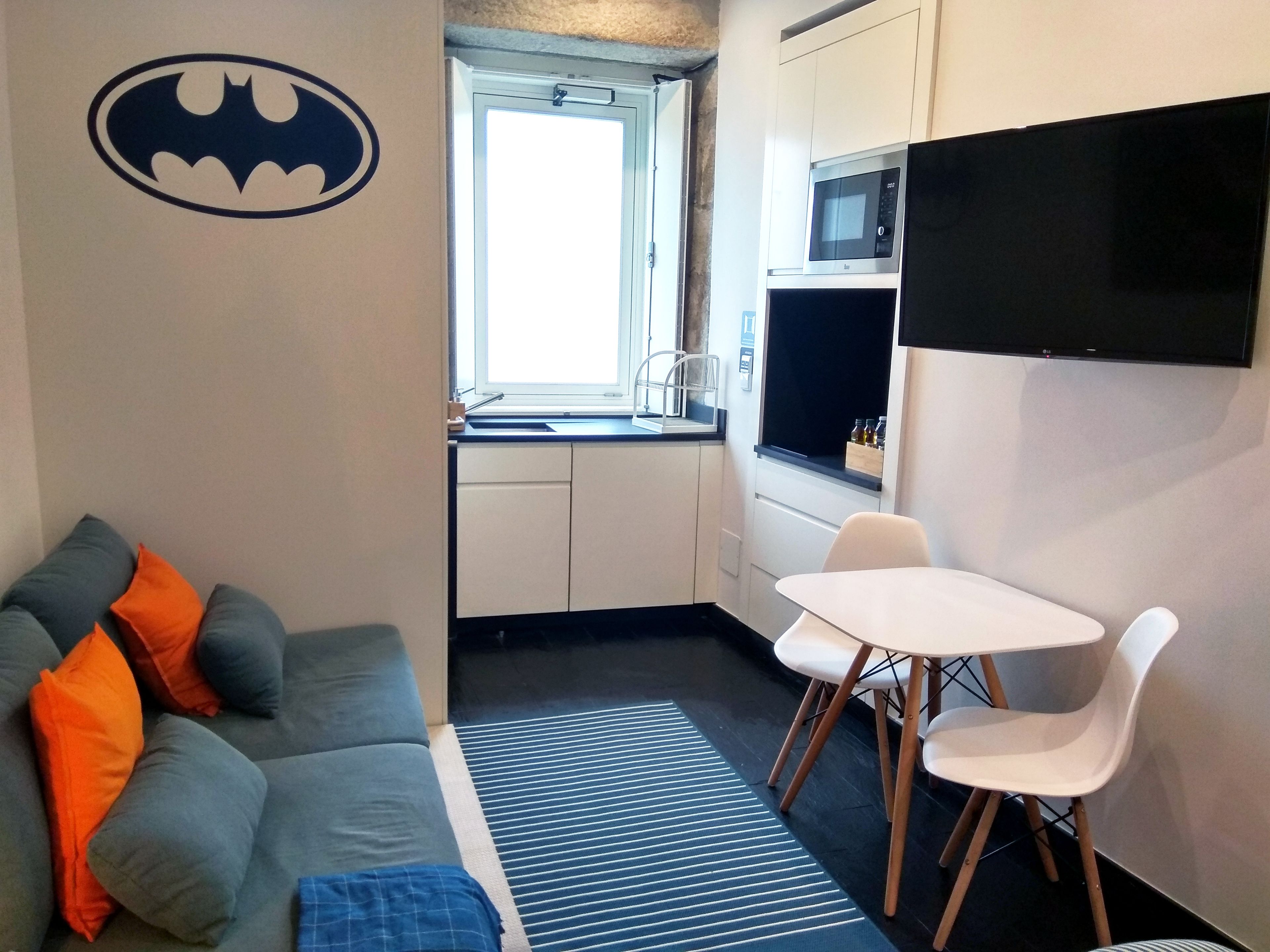 Une pièce compacte comprenant un canapé, une table à manger avec des chaises, un four à micro-ondes et un téléviseur à écran plat.