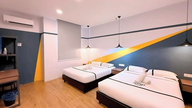 Une chambre d’hôtel moderne équipée de deux lits, d’un bureau et d’un appareil de climatisation.