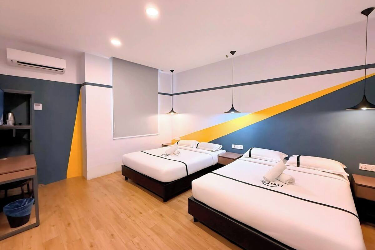 Una habitación de hotel moderna con dos camas, un escritorio y un equipo de aire acondicionado.