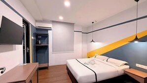 Une chambre d’hôtel moderne équipée d’un lit, d’une table de chevet, d’un bureau et d’un téléviseur fixé au mur.