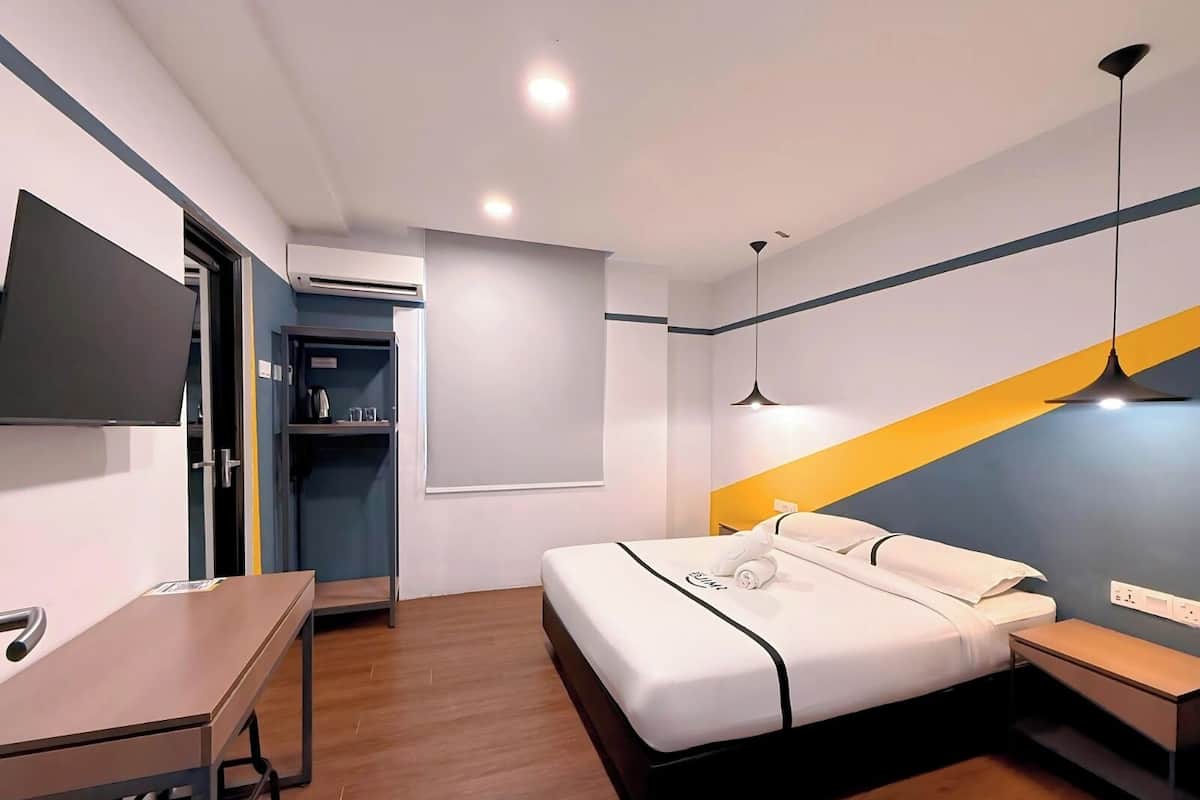 Una habitación de hotel moderna con cama, mesita de noche, escritorio y televisor montado en la pared.