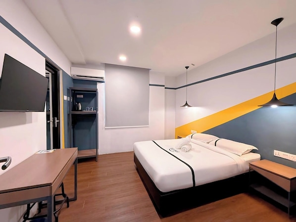 A modern hotel room with a bed, bedside table, desk, and a TV mounted on the wall.
