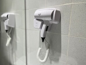 Ein Fön an einer gefliesten Wand.