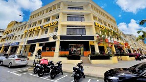 Un hôtel à plusieurs étages, reconnaissable à son grand panneau « HOTEL SMILE », doté de nombreux balcons et disposant d’un parking pour motos et voitures.