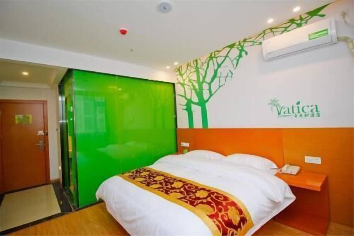 Ein Hotelzimmer mit einem Bett, einer grünen Tür, einer Klimaanlage und einem an der Wand befestigten Schild.